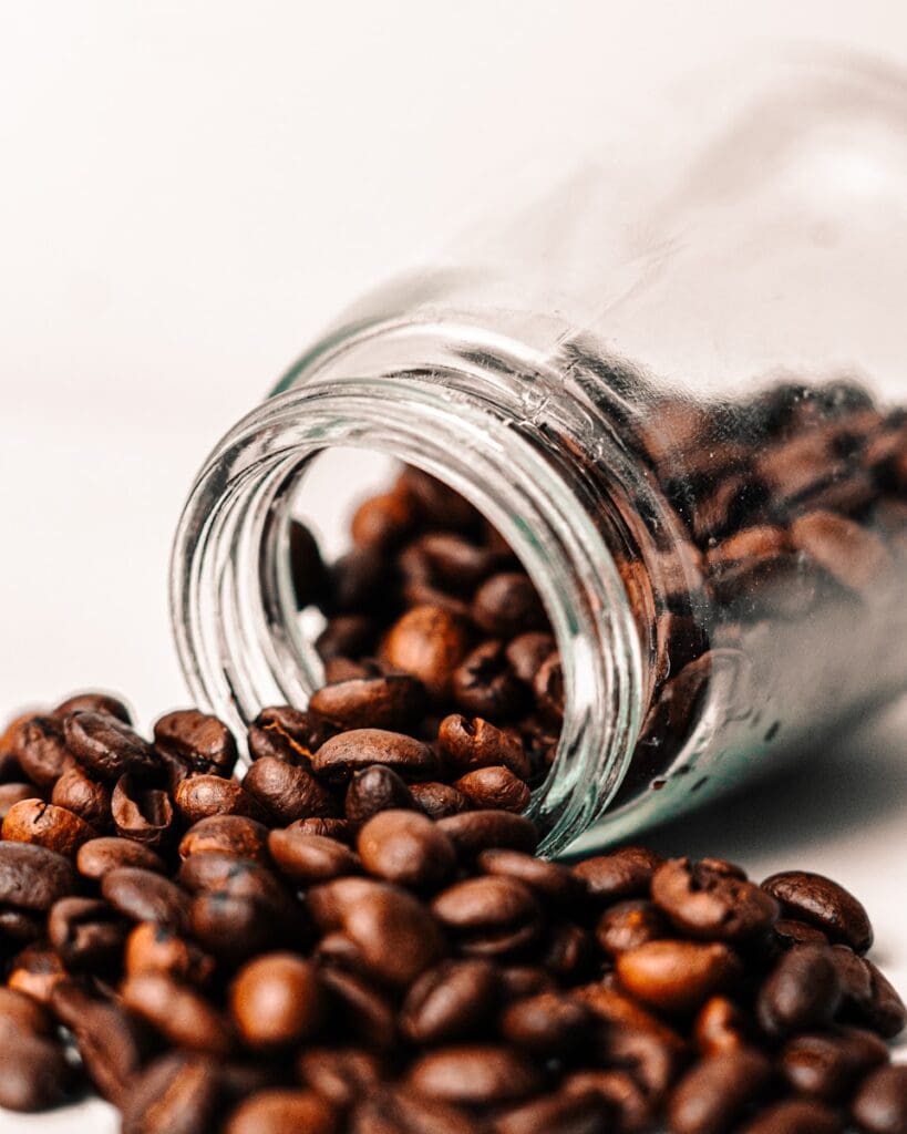 a glass jar filled with coffee beans on top of a white table